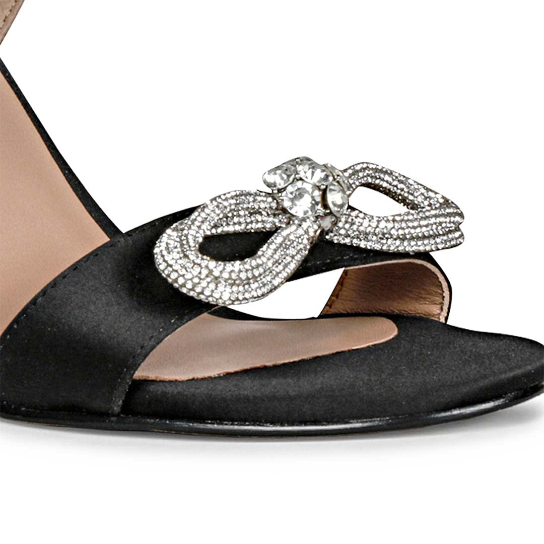 Black leather-satin stilettos by Saint Hayden, adorned with a crystal bow for a chic and stylish vibe.