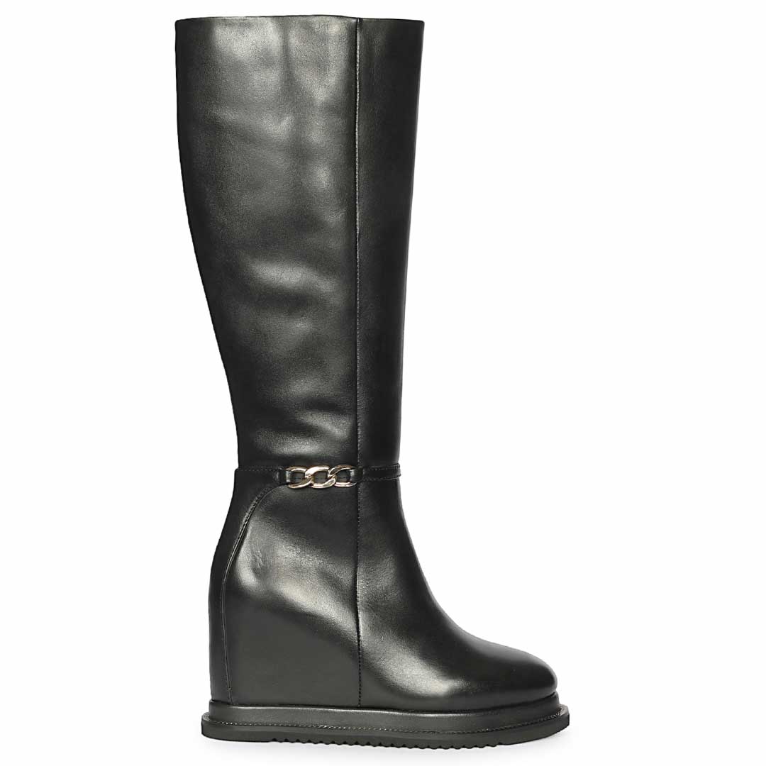 A single black leather knee-high boot with a low wedge heel and a decorative gold-tone chain strap around the ankle