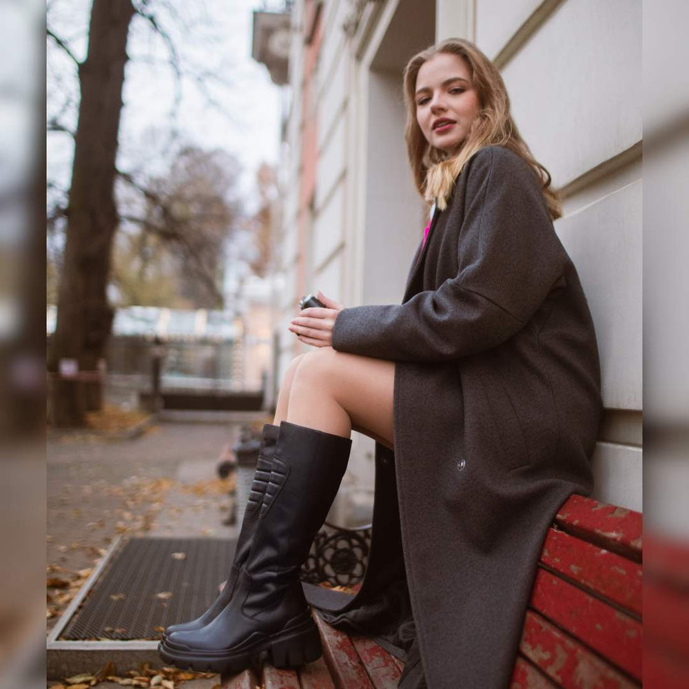 Women's black leather knee high boots by Saint Eloise, styled outdoor lifestyle shot
