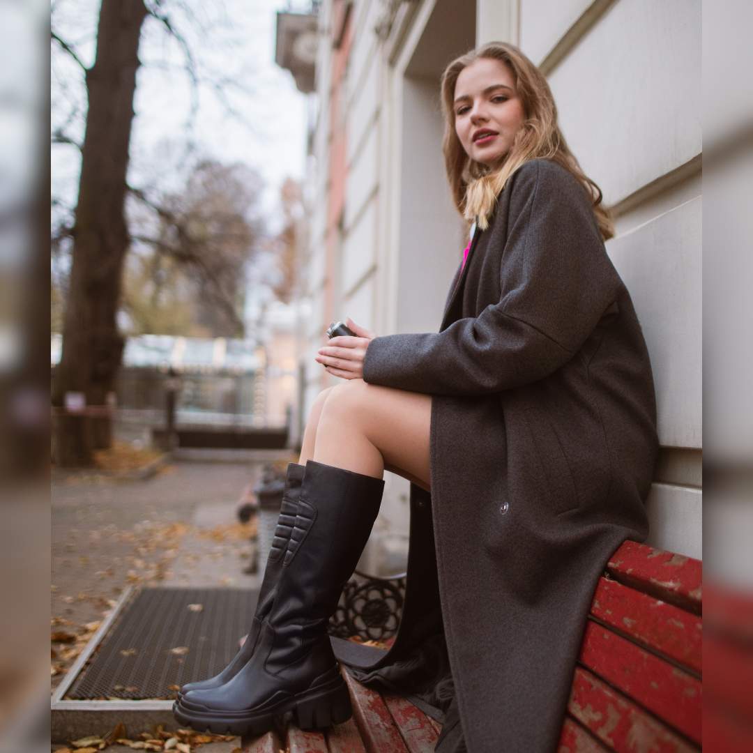 Women's black leather knee high boots by Saint Eloise, styled outdoor lifestyle shot